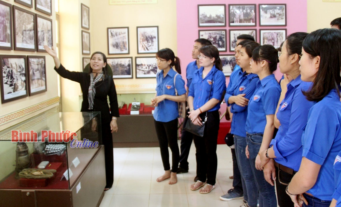 Thuyết minh viên giới thiệu những hình ảnh và hiện vật của Cục hậu cần Miền cho đoàn viên thanh niên Báo Bình Phước