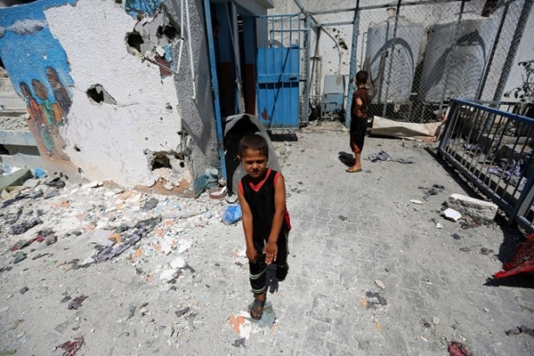 Trẻ em Palestine chơi bên cạnh một lớp học bị phá hủy.