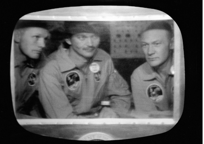 Bên trong buồng cách ly Mobile Quarantine Facility (MQF) là Neil Armstrong, Michael Collins và Edwin E. Aldrin Jr. của tàu Apollo 11 đã đáp xuống Thái Bình Dương, cách phía tây nam đảo Haiwaii khoảng 812 hải lý, chỉ cách tàu sân bay U.S.S. Hornet 12 hải lý