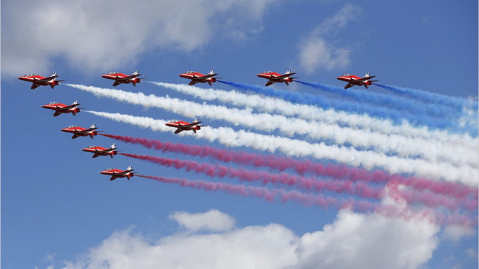 Đội nhào lộn trên không thuộc Không quân Hoàng gia Red Arrows (RAF) thực hiện một chuyến bay qua sân bay Farnborough để mở màng triển lãm quốc tế FIA 2014 tại Farnborough, Anh