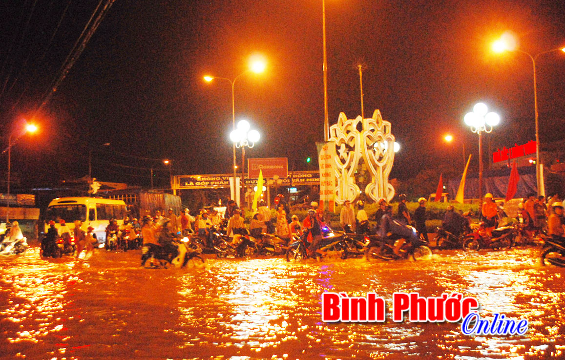 Vì nước ngập nên có nhiều người cùng với xe máy phải đứng trên vòng xoay Hùng Vương chờ nước rút