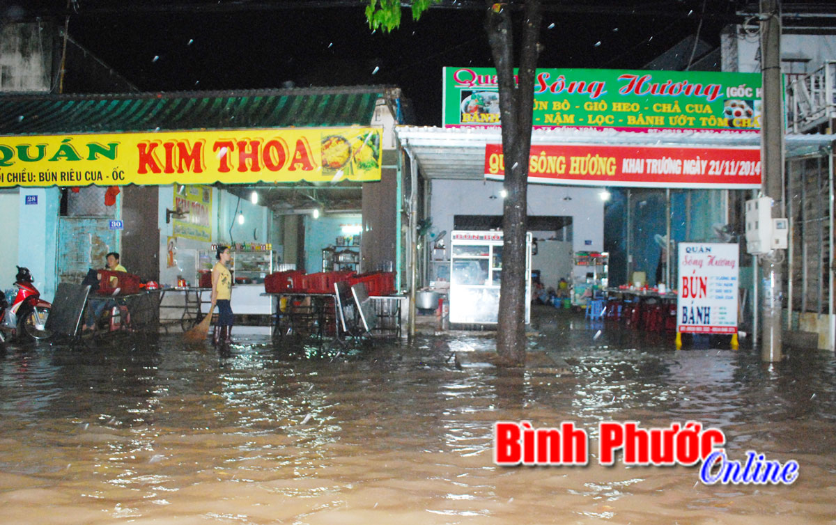 Nước ngập lên vỉa hè tràn vào các cửa, quán ăn hai bên đường Phú Riềng Đỏ