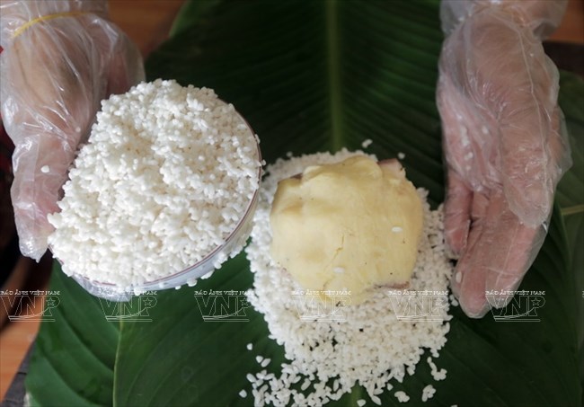 Khi g&oacute;i b&aacute;nh, gạo nếp được đổ tr&ecirc;n l&aacute; b&aacute;nh cho nh&acirc;n b&aacute;nh rồi cho hết b&aacute;t gạo. (Ảnh: Trịnh Văn Bộ/B&aacute;o ảnh Việt Nam)