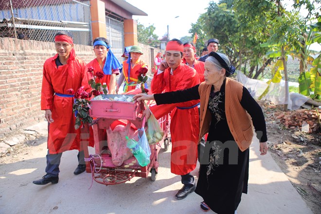 Nhiều người d&acirc;n đặt tiền cho đo&agrave;n rước kiệu cầu mong một năm mới được b&igrave;nh an, may mắn. (Ảnh: Minh Sơn/Vietnam+)