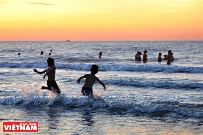  Những em bé nghịch sóng trên biển Sầm Sơn lúc bình minh. Ảnh: Công Đạt