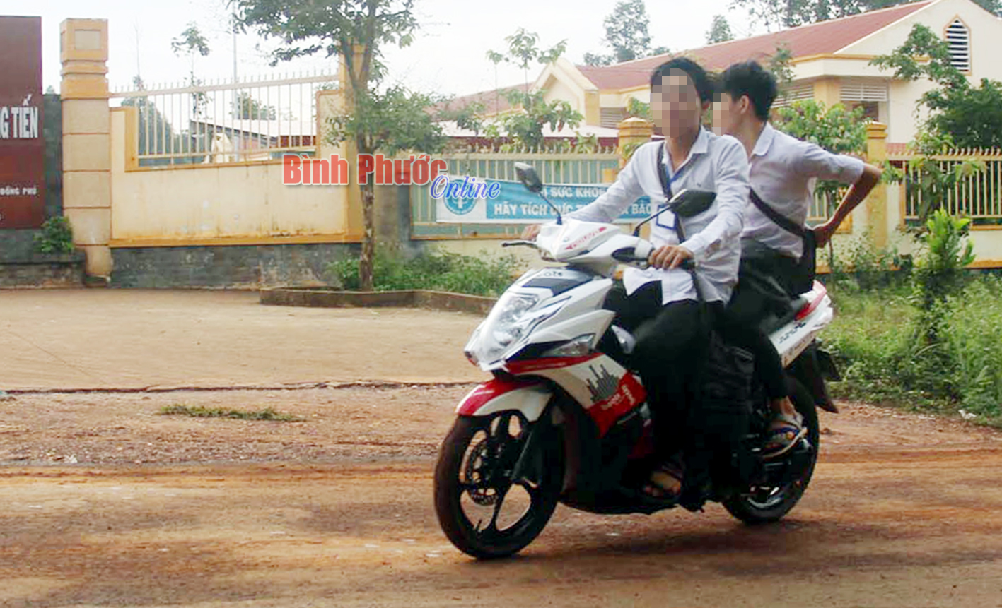 Hai học sinh Trường cấp 2-3 Đồng Tiến đi xe phân khối lớn và không đội mũ bảo hiểm đến trường.