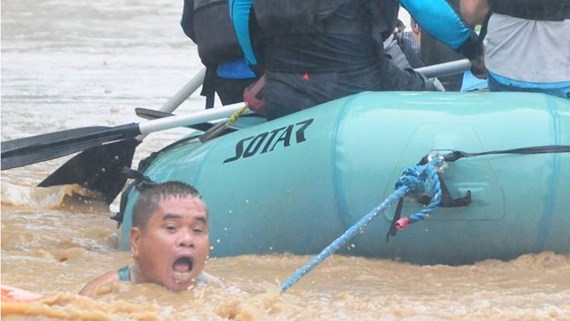 Một người cố bám vào sợi dây thừng của xuồng cứu hộ trong lúc phải sơ tán vì ngập lụt nghiêm trọng ở thành phố Cagayan de Oro của Philippines ngày 22-12-2017. Ảnh: REUTERS