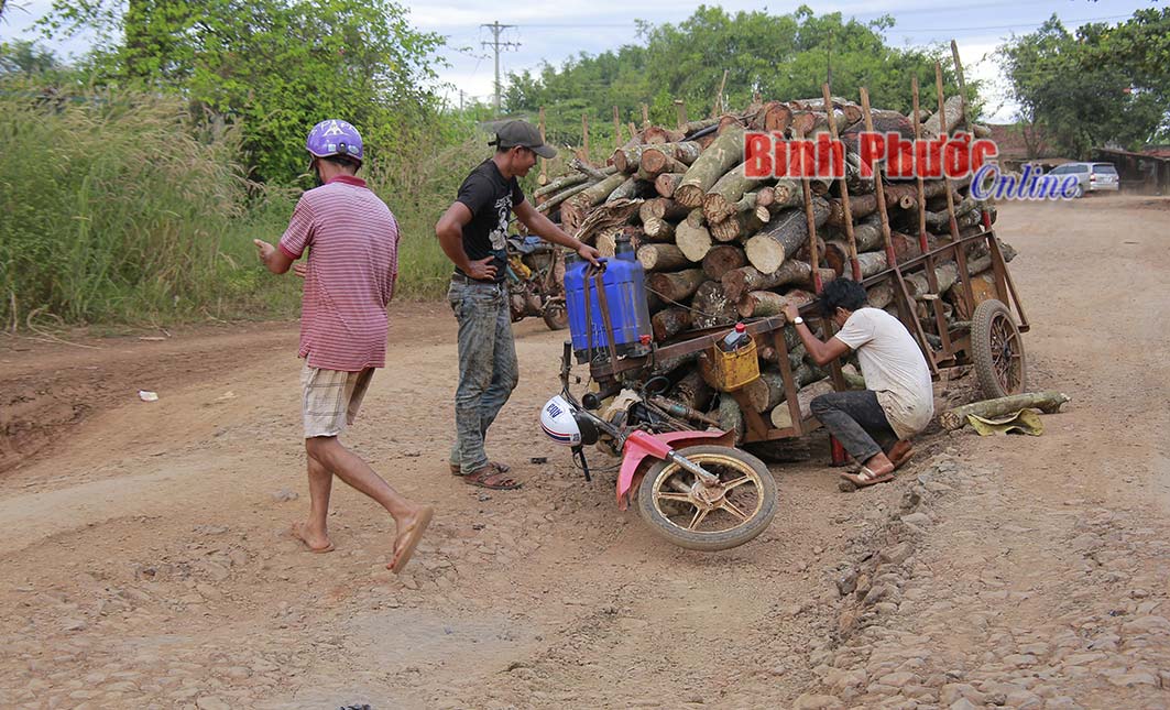 Một xe tự chế chở củi của người d&acirc;n x&atilde; An Khương khi qua ng&atilde; ba 304 bị sụp b&aacute;nh do đất đ&aacute; tr&ecirc;n mặt đường dồn th&agrave;nh luống.