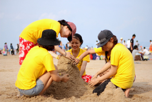 Nhóm bạn trẻ đắp cát trên bãi biển. Ảnh: Nguyễn Khoa