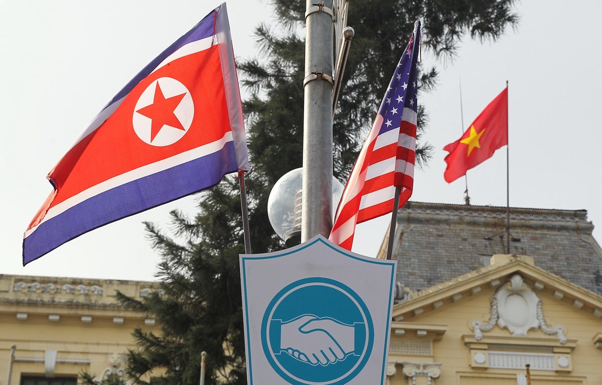 Cờ Hoa Kỳ và cờ Triều Tiên, bên dưới là biểu tượng hai bàn tay bắt chặt vào nhau thể hiện tinh thần của cuộc gặp lớn, được treo bên ngoài Nhà khách Chính phủ trên phố Ngô Quyền, Quận Hoàn Kiếm. (Ảnh: Lâm Khánh/TTXVN)