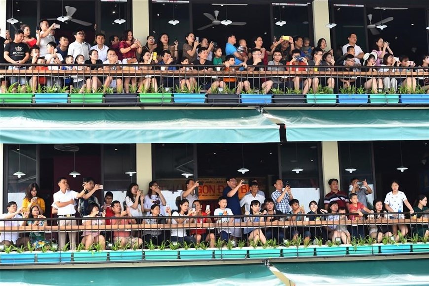  Không chỉ tụ tập đông ở hai bên đường Hồ Xuân Hương, nhiều người dân và du khách đã lựa chọn chỗ ngồi trên các tòa nhà cao tầng để có vị trí đẹp nhất để chiêm ngưỡng và quay lại hình ảnh của Carnival Đường phố Sầm Sơn. (Ảnh: PV)