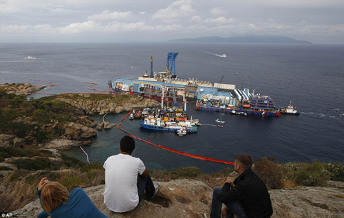 Người d&acirc;n theo d&otilde;i cảnh lật cứu hộ con t&agrave;u khổng lồ.