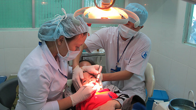 Các bác sĩ ở Bệnh viện Nhi Đồng 1 trám răng cho bệnh nhi L.H.L. - Ảnh: Thùy DƯơng
