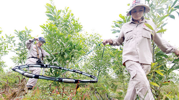 Hai nữ kỹ thuật viên Trần Thị Hạnh và Trần Thị Lý sử dụng máy dò tín hiệu tìm bom đạn dưới lòng đất thôn Trung Long, xã Triệu Ái, huyện Triệu Phong (Quảng Trị)