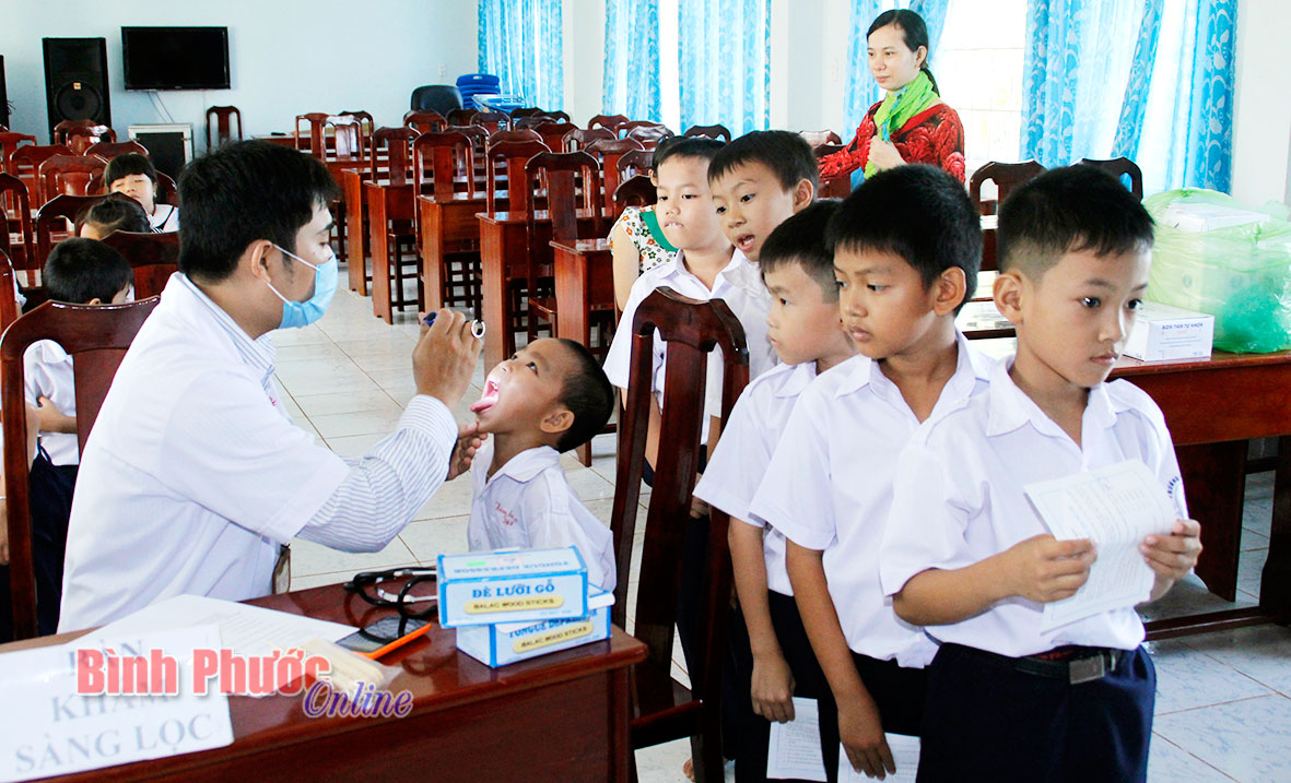 Nhân viên Trạm y tế phường Tân Phú kiểm tra sức khỏe trước tiêm chủng cho học sinh Trường tiểu học Tân Phú B, thị xã Đồng Xoài - Ảnh: S.H