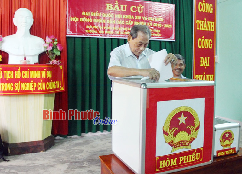 Cử tri Nguyễn Phương Nam, 65 năm tuổi Đảng bỏ lá phiếu đầu tiên vào thùng phiếu tại tổ bầu cử số 4, khu phố Phước Thiện