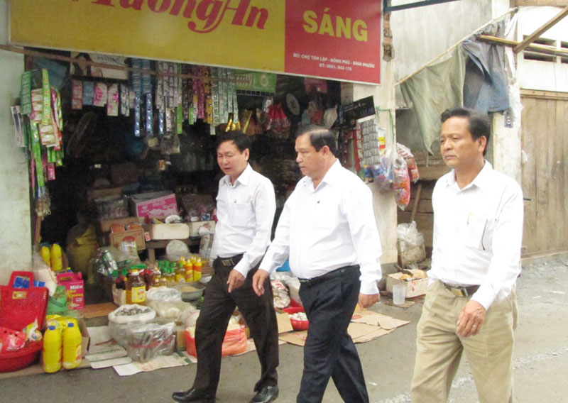 Chủ tịch UBND tỉnh Nguyễn Văn Trăm (đi giữa) tham quan chợ xã Tân Lập