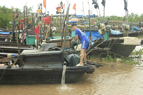 Ngư dân ở khu vực cống Đen bơm nước ra khỏi thuyền