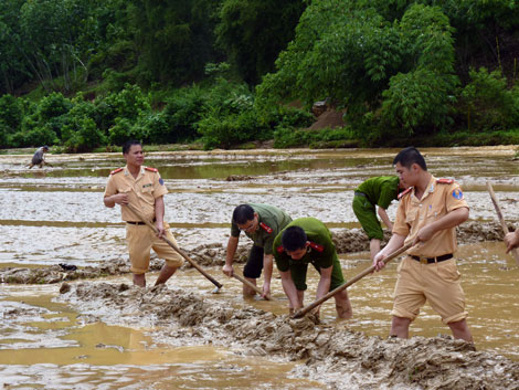 Lực lượng công an tỉnh Sơn La hỗ trợ người dân đắp lại bờ ruộng bị ngập để chuẩn bị gieo cấy đợt 2
