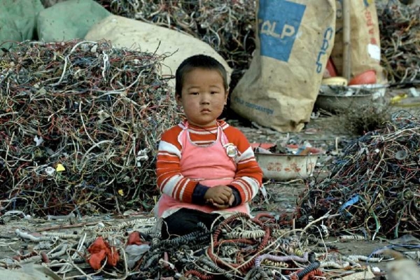 Em bé ngồi làm việc giữa đống rác thải công nghệ vô cùng độc hại. Trung Quốc đã dần trơ thành bãi rác đồ điện tử của cả thể giới.  
