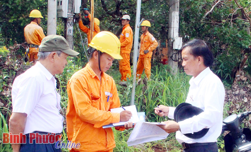 Trưởng khu phố 1 Nguyễn Thanh Hùng (bìa phải) cùng người dân khu phố phối hợp Điện lực thị xã Phước Long hoàn thiện hệ thống đèn điện chiếu sáng