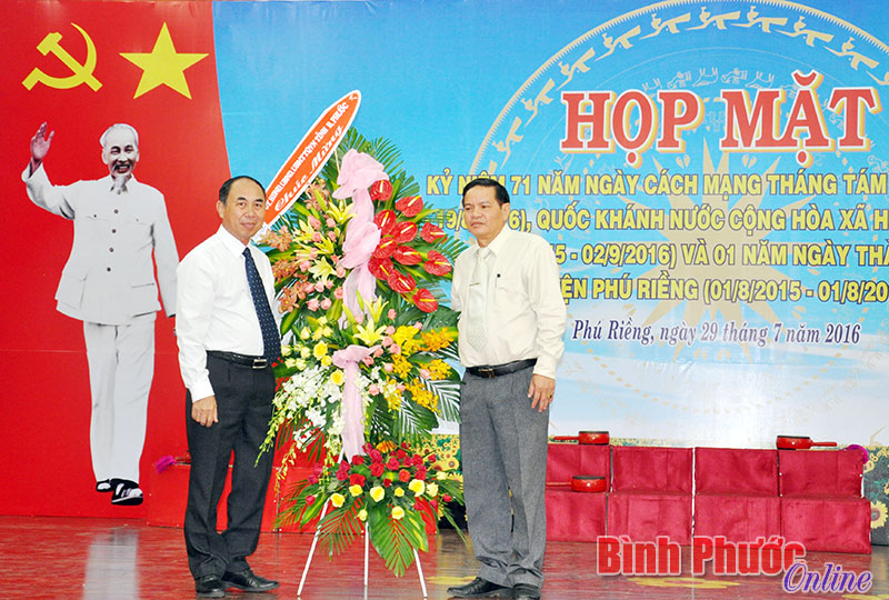 Phó chủ tịch UBND tỉnh Nguyễn Tiến Dũng (bên trái) tặng lẵng hoa của Tỉnh ủy, HĐND, UBND, Ủy ban MTTQVN tỉnh cho Đảng bộ, chính quyền và nhân dân huyện Phú Riềng