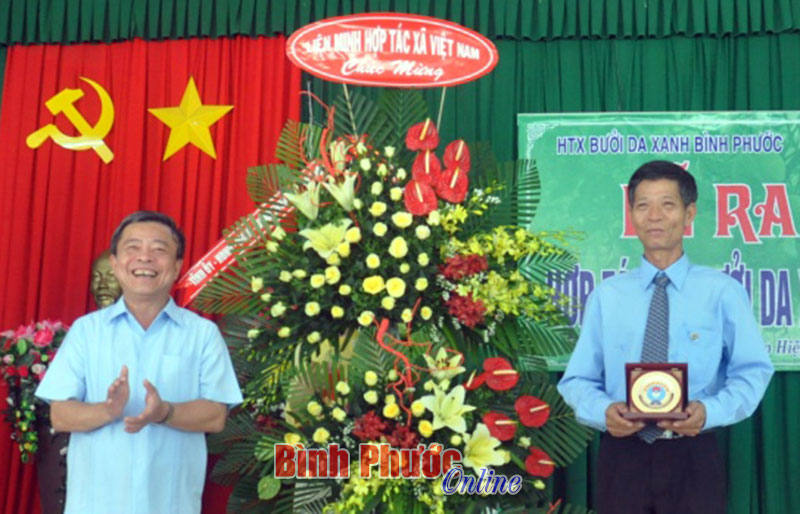 Chủ tịch Liên minh HTX Việt Nam Võ Kim Cự trao lẵng hoa chúc mừng HTX bưởi da xanh Bình Phước