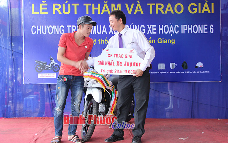 Ông Đào Văn Giang, Giám đốc Công ty TNHH Tuấn Giang trao giải nhất là chiếc xe máy Yamaha Jupiter Gravita trị giá 28.600.000 đồng cho khách hàng Nguyễn Minh Tuấn tạm trú tại khu phố Bàu Ké, thị trấn Tân Phú, huyện Đồng Phú