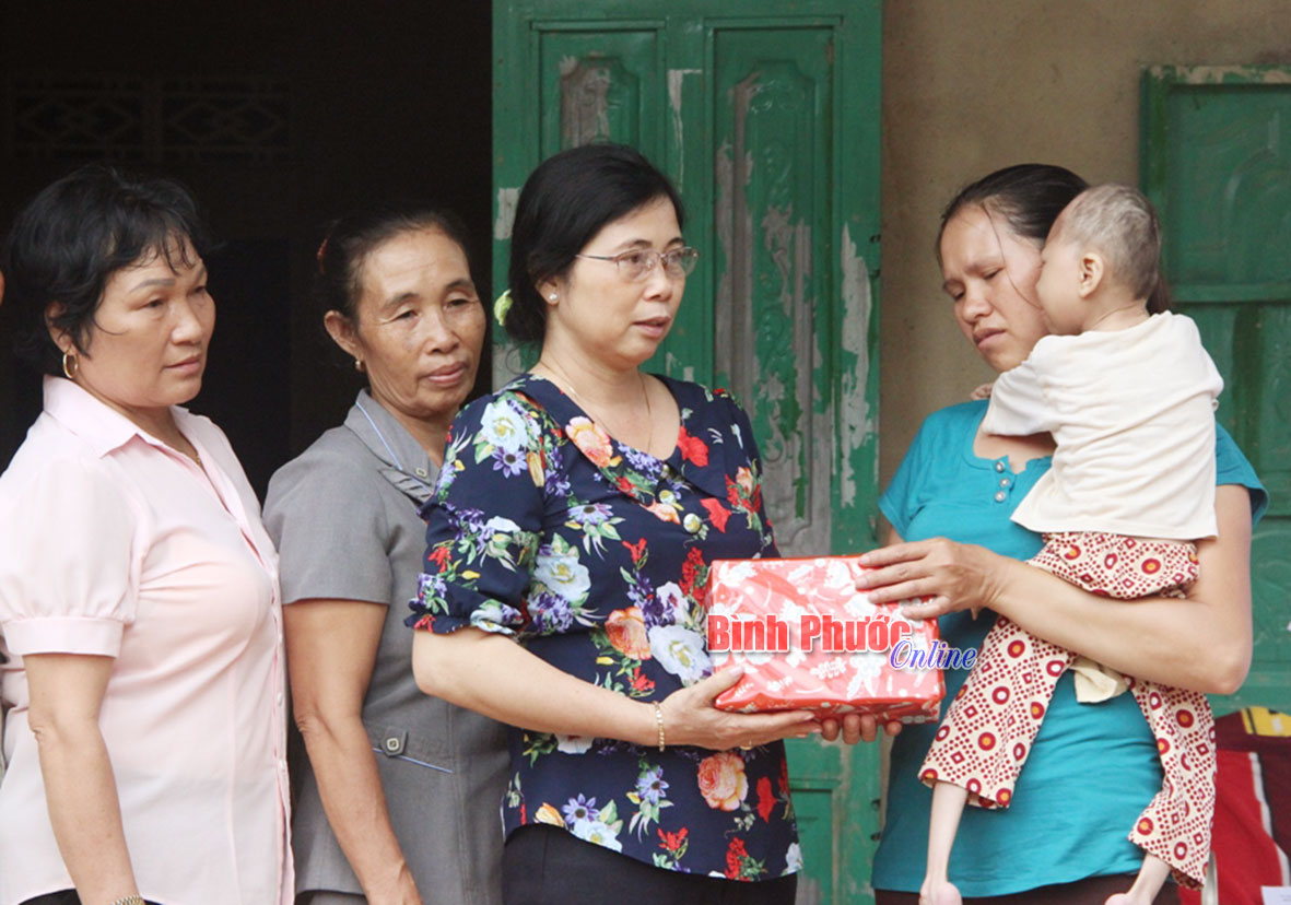 Chủ tịch Hội Liên hiệp Phụ nữ huyện Bù Đăng Nguyễn Thị Hoa (trái) trao quà cho gia đình chị Nông Thị Quy