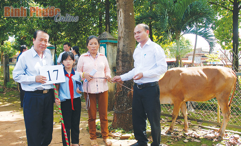 Phó chủ tịch UBND huyện Bù Đăng Lương Hận (bên trái) trao bò cho hộ đồng bào nghèo ở xã Bom Bo