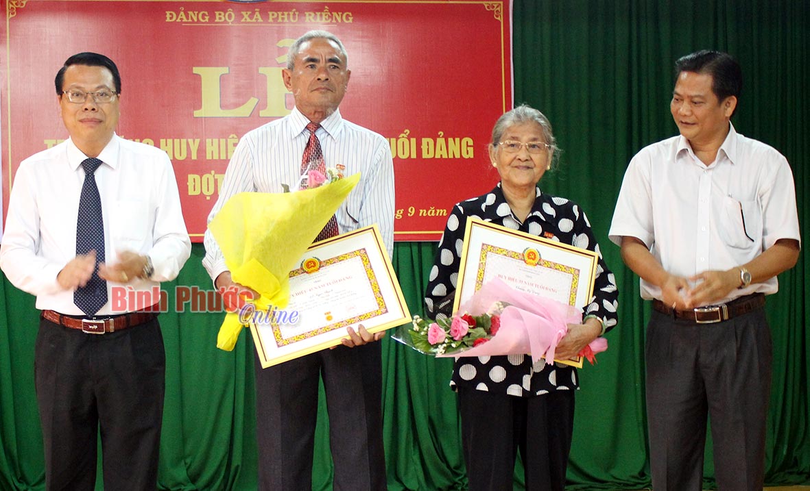 Đảng viên Chung Mỹ Dung và đảng viên Đỗ Ngọc Thạch nhận huy hiệu Đảng tại buổi lễ