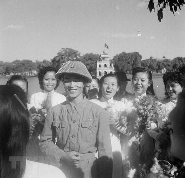 Nữ sinh Hà Nội đón chào Thiếu tướng Vương Thừa Vũ, Chủ tịch Ủy ban Quân chính Hà Nội, người dẫn đầu đoàn quân chiến thắng về giải phóng Thủ đô. (Ảnh: Tư liệu TTXVN)