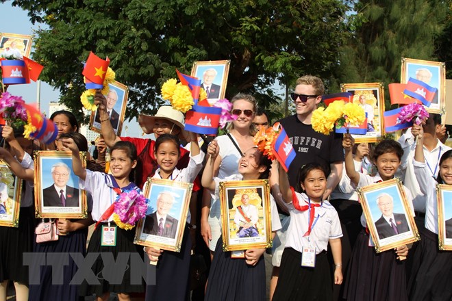 Khách nước ngoài chụp ảnh lưu niệm với các em học sinh Việt kiều tham gia đón đoàn. (Ảnh: Minh Hưng/TTXVN)