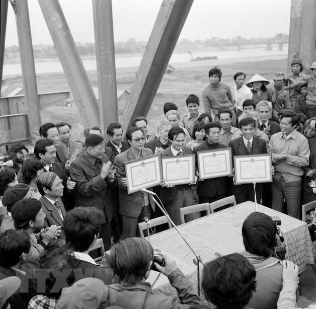  Bộ trưởng Bộ Giao th&ocirc;ng vận tải Đồng Sĩ Nguy&ecirc;n (người &aacute;o sẫm vỗ tay, cạnh người đeo k&iacute;nh nhận bằng khen) trao bằng khen cho 4 đơn vị tham gia x&acirc;y dựng cầu Chương Dương tại lễ nối liền dầm cầu Chương Dương, ng&agrave;y 17/2/1985. Thời gian đ&oacute;, &ocirc;ng l&agrave; người ki&ecirc;n quyết bảo vệ phương &aacute;n phải x&acirc;y dựng cầu Chương Dương khi ch&uacute;ng ta định chỉ l&agrave;m duy nhất cầu Thăng Long bắc qua s&ocirc;ng Hồng tại địa b&agrave;n Thủ đ&ocirc;. (Ảnh: Bảo Hanh/TTXVN)