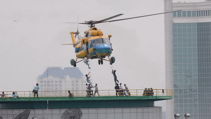 Các nạn nhân leo lên hai thang dây của chiếc trực thăng đang treo lơ lửng trên tòa nhà