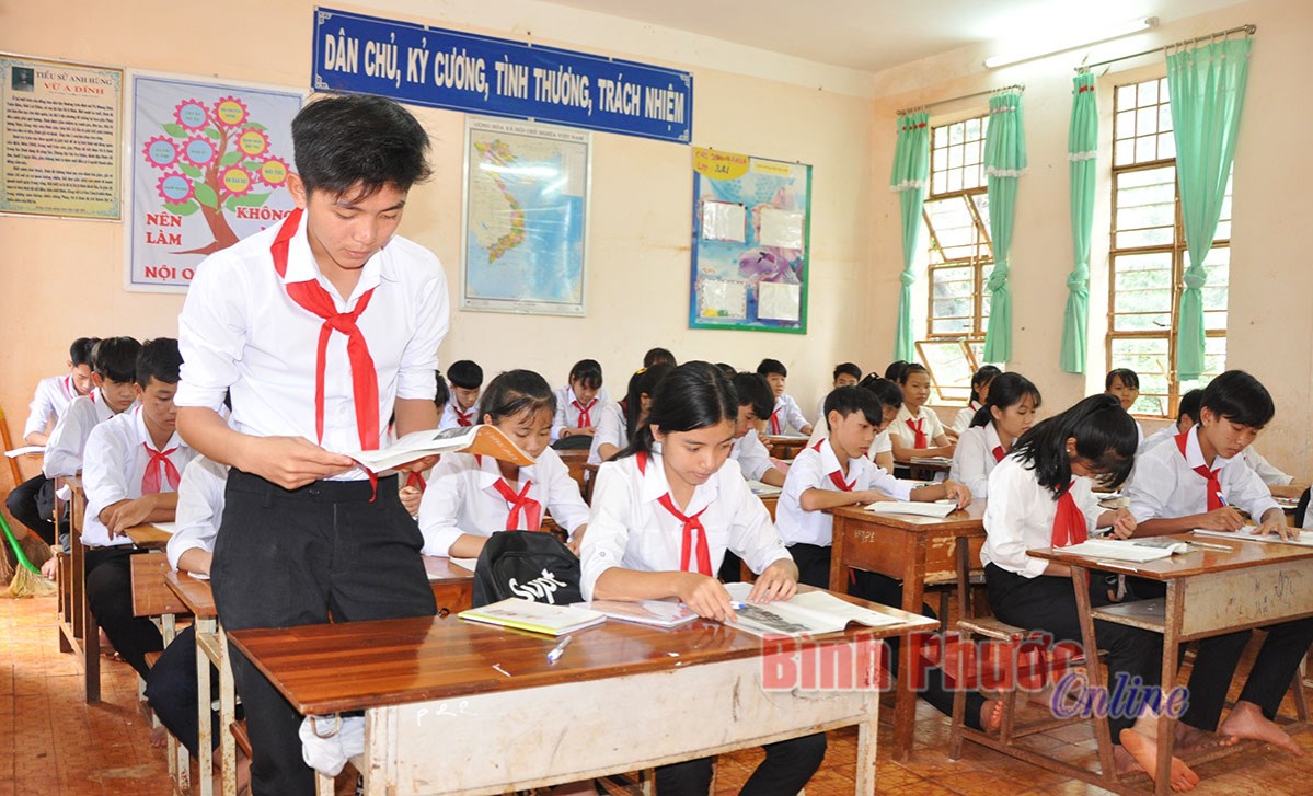 Học sinh cấp 2 khom lưng ngồi bàn ghế cấp 1