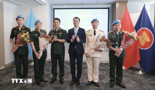 Đại sứ, Trưởng Phái đoàn Đại diện thường trực Việt Nam tại Liên hợp quốc Đặng Hoàng Giang tặng hoa, chúc mừng các sỹ quan thuộc lực lượng Gìn giữ Hòa bình của Bộ Quốc phòng và Bộ Công an Việt Nam đang làm việc tại Cục Hoạt động Hoà bình Liên hợp quốc. (Ảnh: Thanh Tuấn/TTXVN) TTXVN_2505gingiuhoabinh1.jpeg